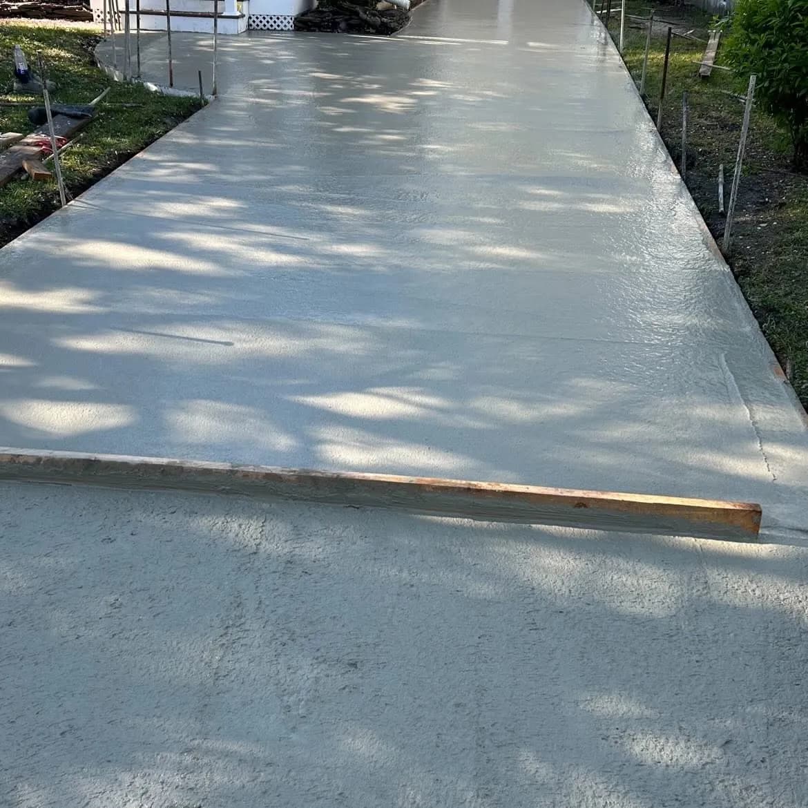 Freshly poured concrete driveway slab floated smooth between formed wood edges during finishing in South Jersey
