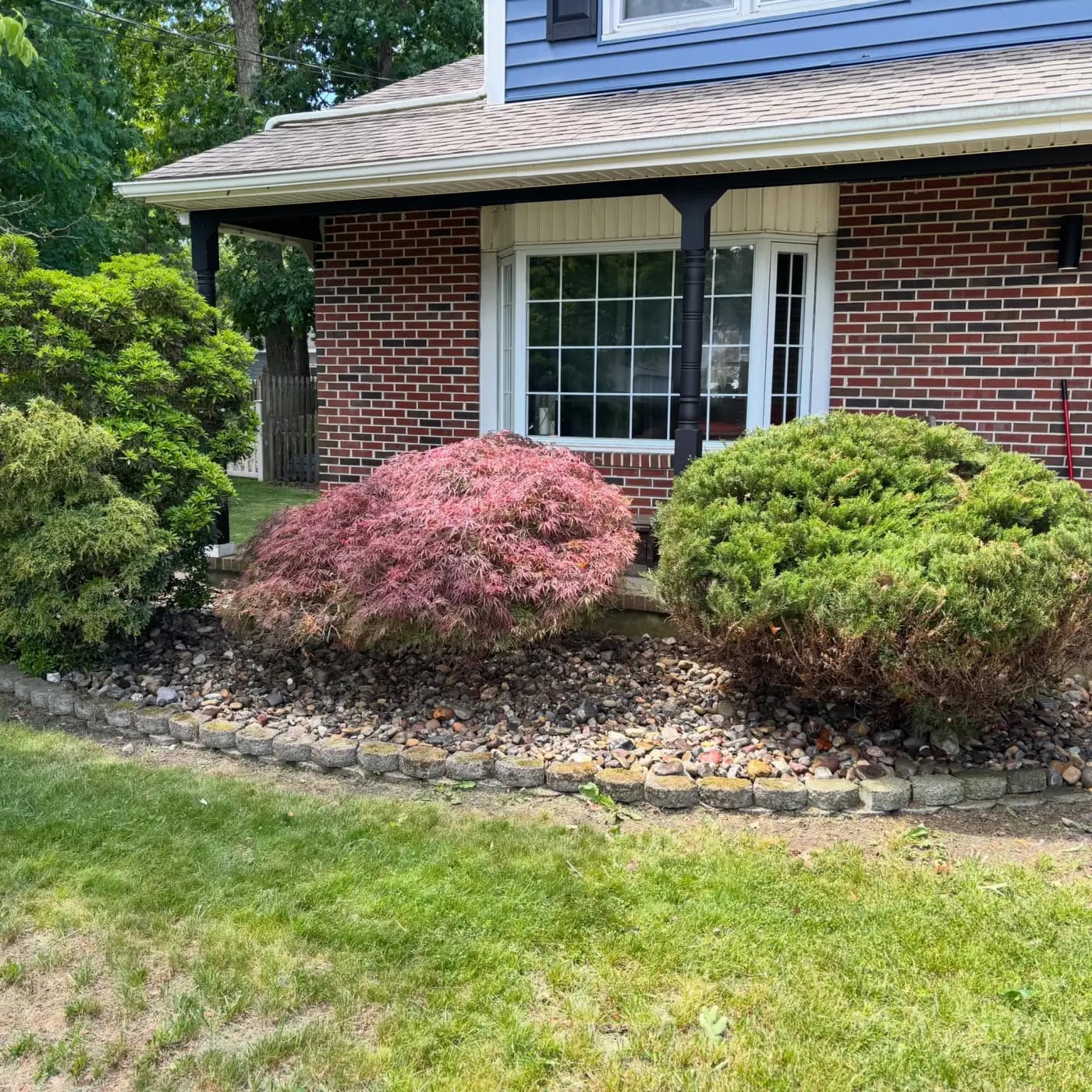 Rock garden bed border around fresh mulch and shrubs in New Jersey