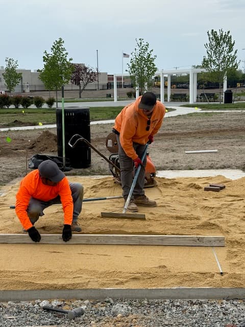 Crew screeding a compacted sand base for a paver patio in Galloway, NJ