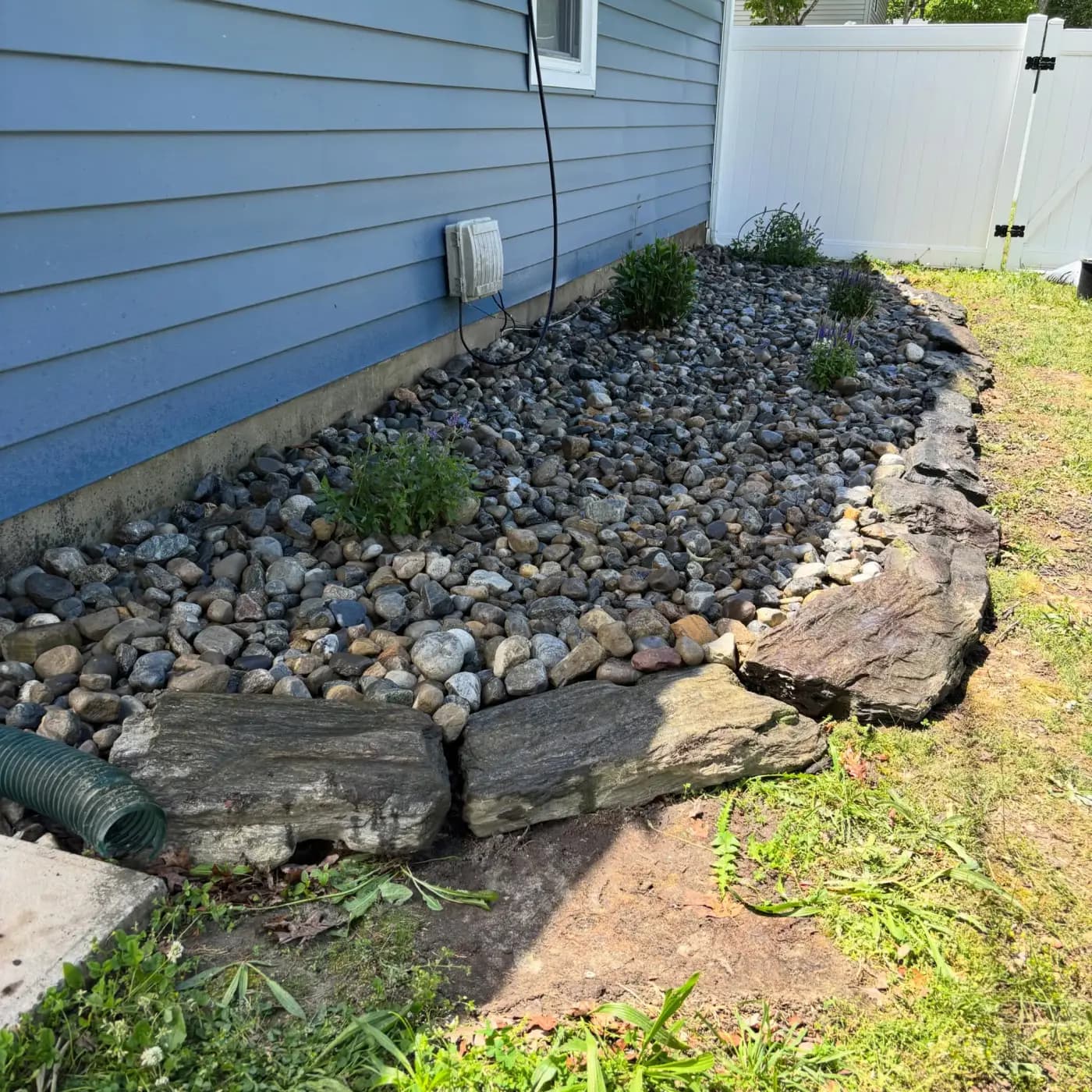 River-rock drainage bed channeling runoff in a South Jersey yard